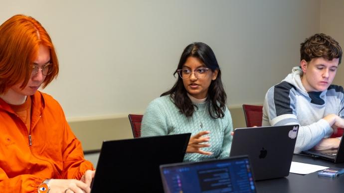 Gaya Rajamony (center) speaks in class while her classmates around her work on laptops