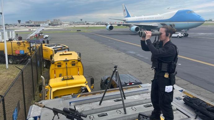 Kim Sayles uses binoculars while standing guard at the Air Force 1 runway